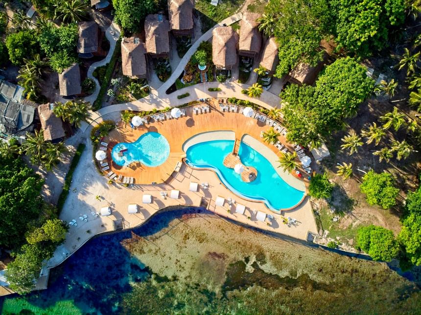 Ariel top view of Hotel Isla Del Encanto with palm trees, pool, and ocean view