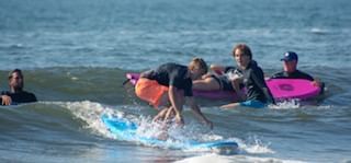 People taking a surf lesson in Diamond Beach in the waves near our Wildwood Crest hotel