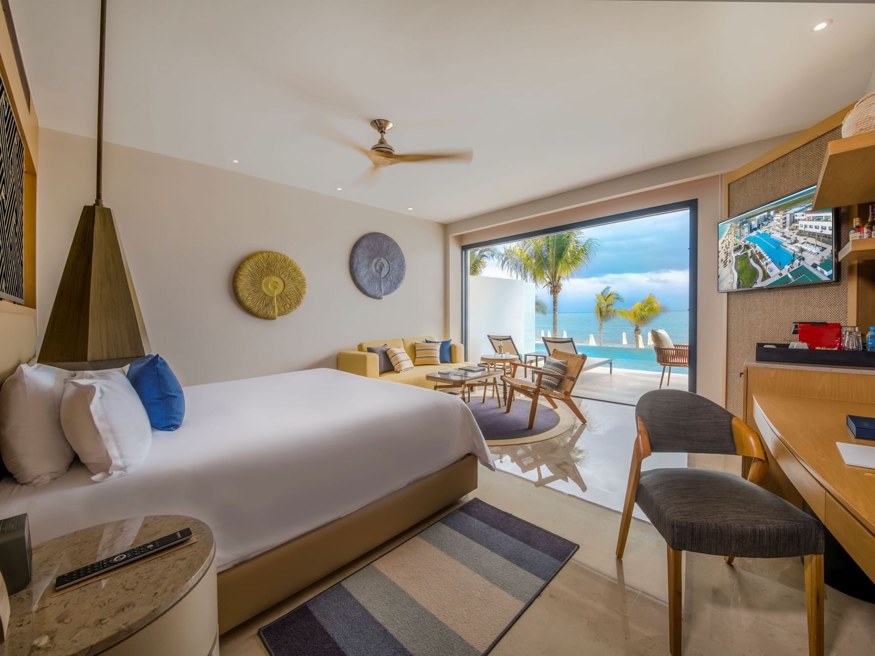 King bed with comfy pillows, work desk, TV & sofa of Junior Suite Ocean Front View at Heaven Resort