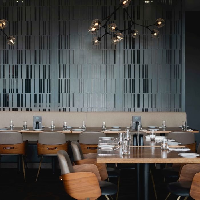 Karinyas Restaurant interior with wooden tables, chairs, and stylish pendant lights at Mercure Kooindah Waters