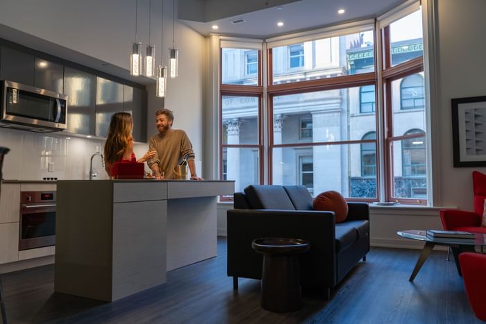Couple by a kitchen with large windows in the suite at ReStays Ottawa