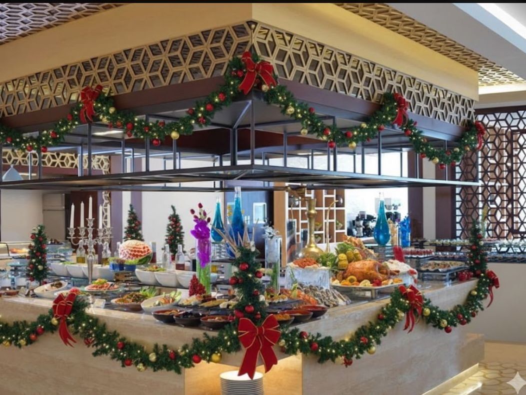 A festive buffet table decorated with Christmas garlands, bows, and ornaments, showcasing various dishes.