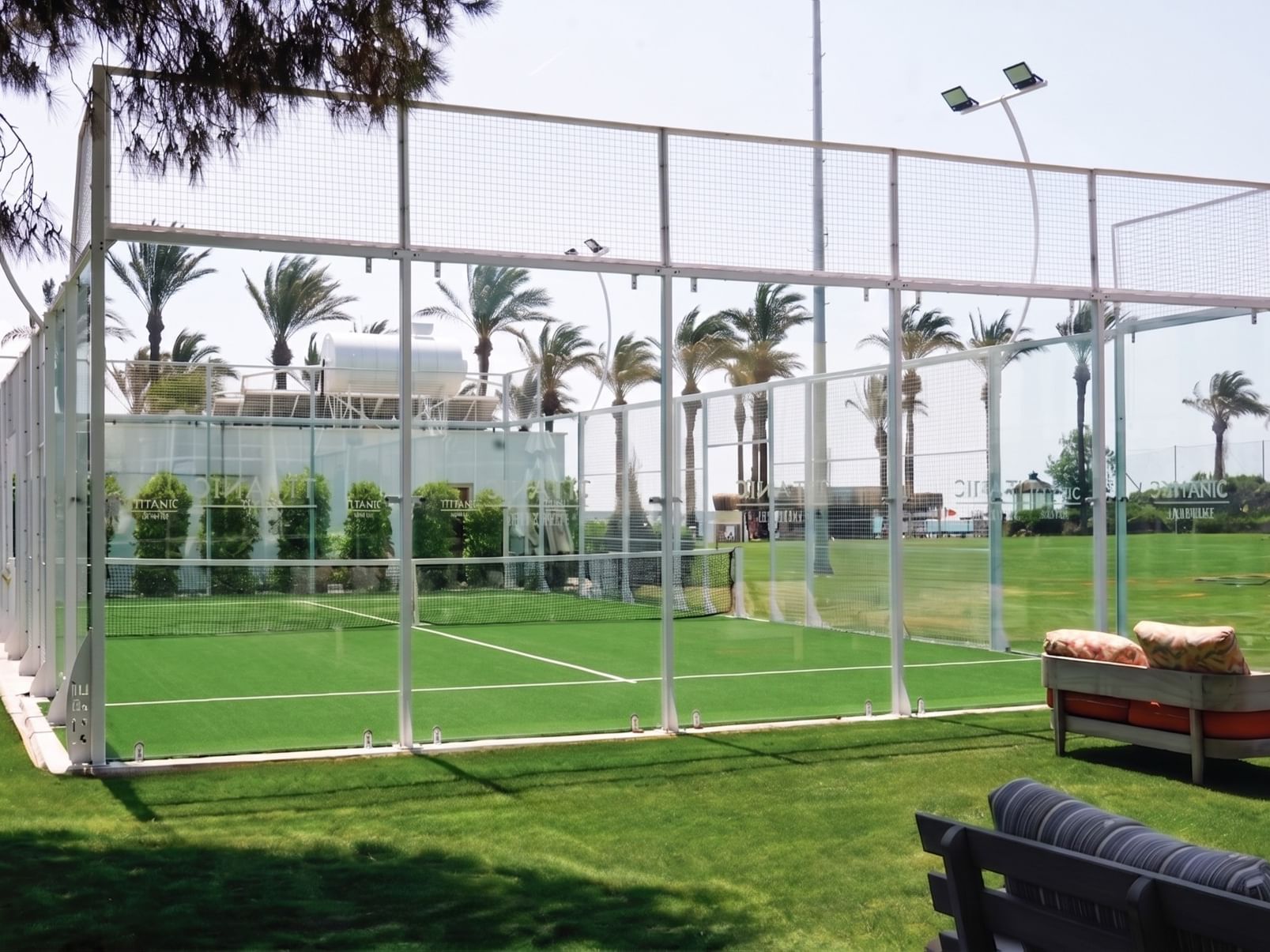 At Titanic Deluxe Lara in Antalya, a padel court surrounded by glass and lush greenery.