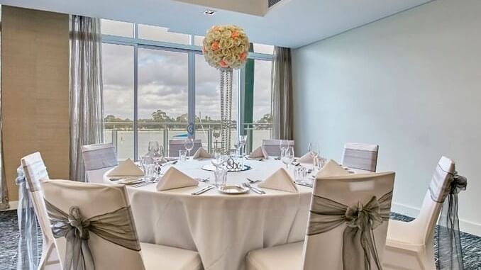 Elegant wedding table at The Sebel Mandurah, featuring formal place settings and a floral centerpiece with a lake view