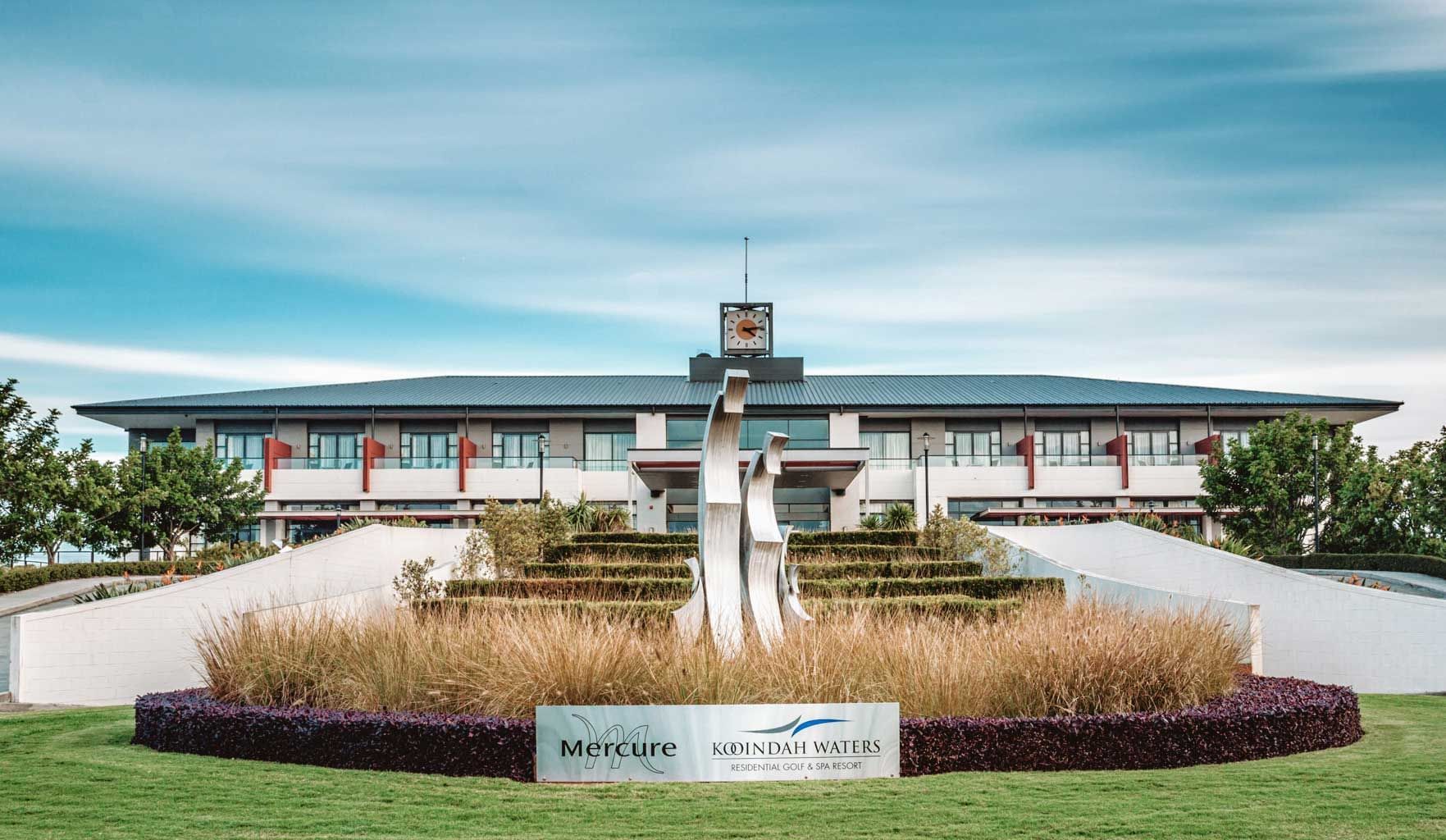 Modern exterior of Mercure Kooindah Waters with a sculpture in front, under a blue sky