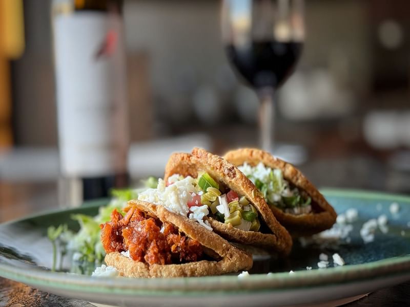 Three gorditas with various fillings and a glass of wine served in La Distral Querétaro at Grand Fiesta Americana