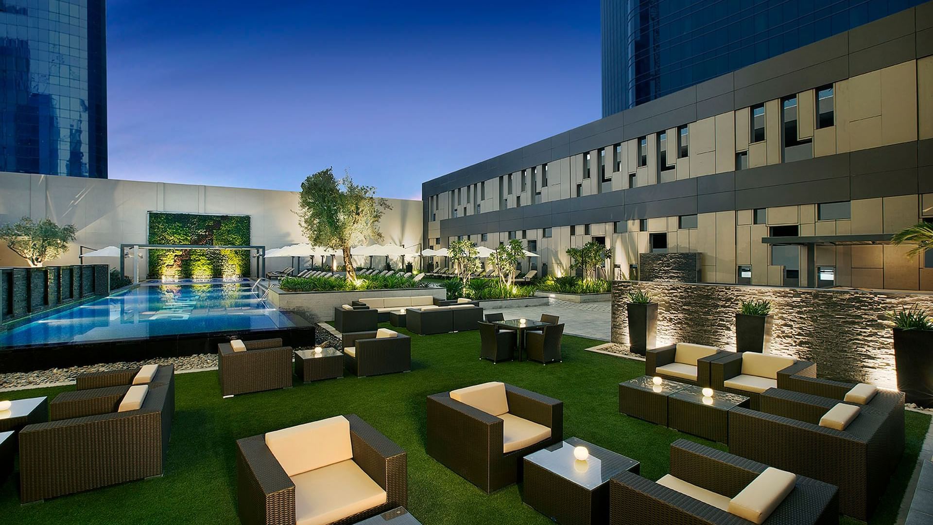 Outdoor lounge area located next to the pool with chairs & tables at DAMAC Maison Cour Jardin