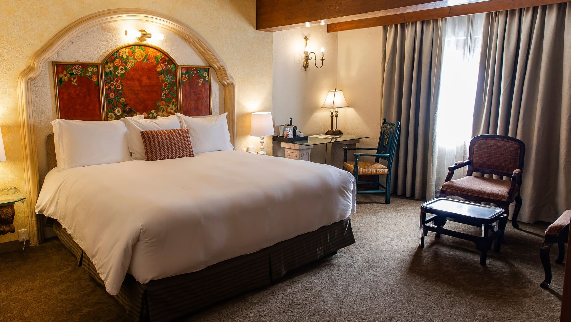 King Grand Class room with ornate floral headboard, white bedding, and elegant seating area at Quinta Real Zacatecas