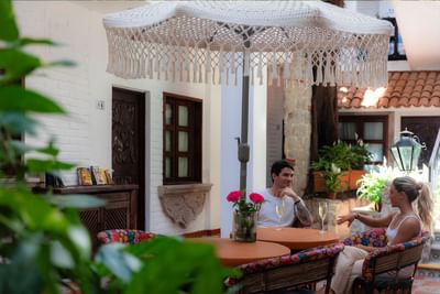 Couple enjoying champagne at outdoor table with macrame umbrella and red roses at Casa Dona Susana