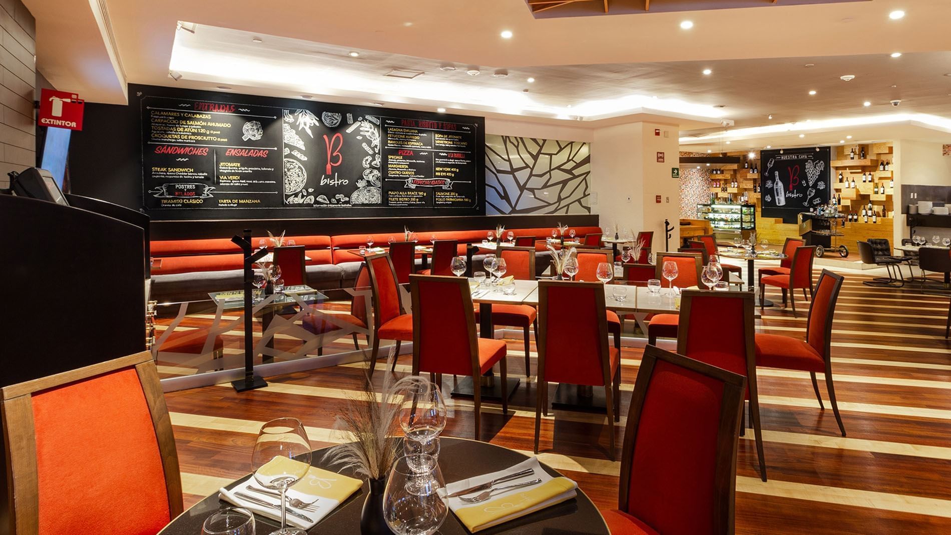 Bistro dining room featuring red chairs and a large chalkboard menu wall at Camino Real Polanco Mexico