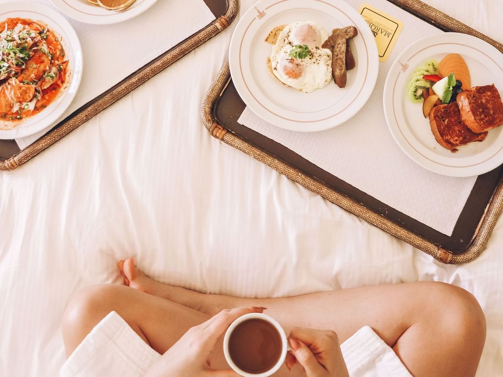 Una niña cenando en una cama en una habitación en Marquis Los Cabos