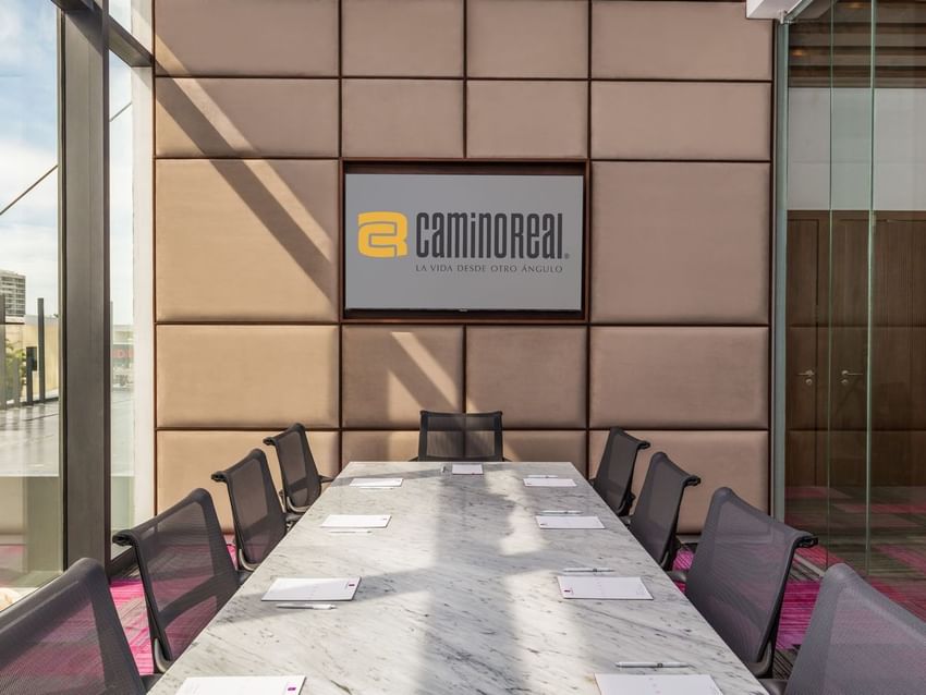 Salón Mérida meeting room featuring a marble table, ergonomic chairs, and a large wall screen at Camino Real Merida