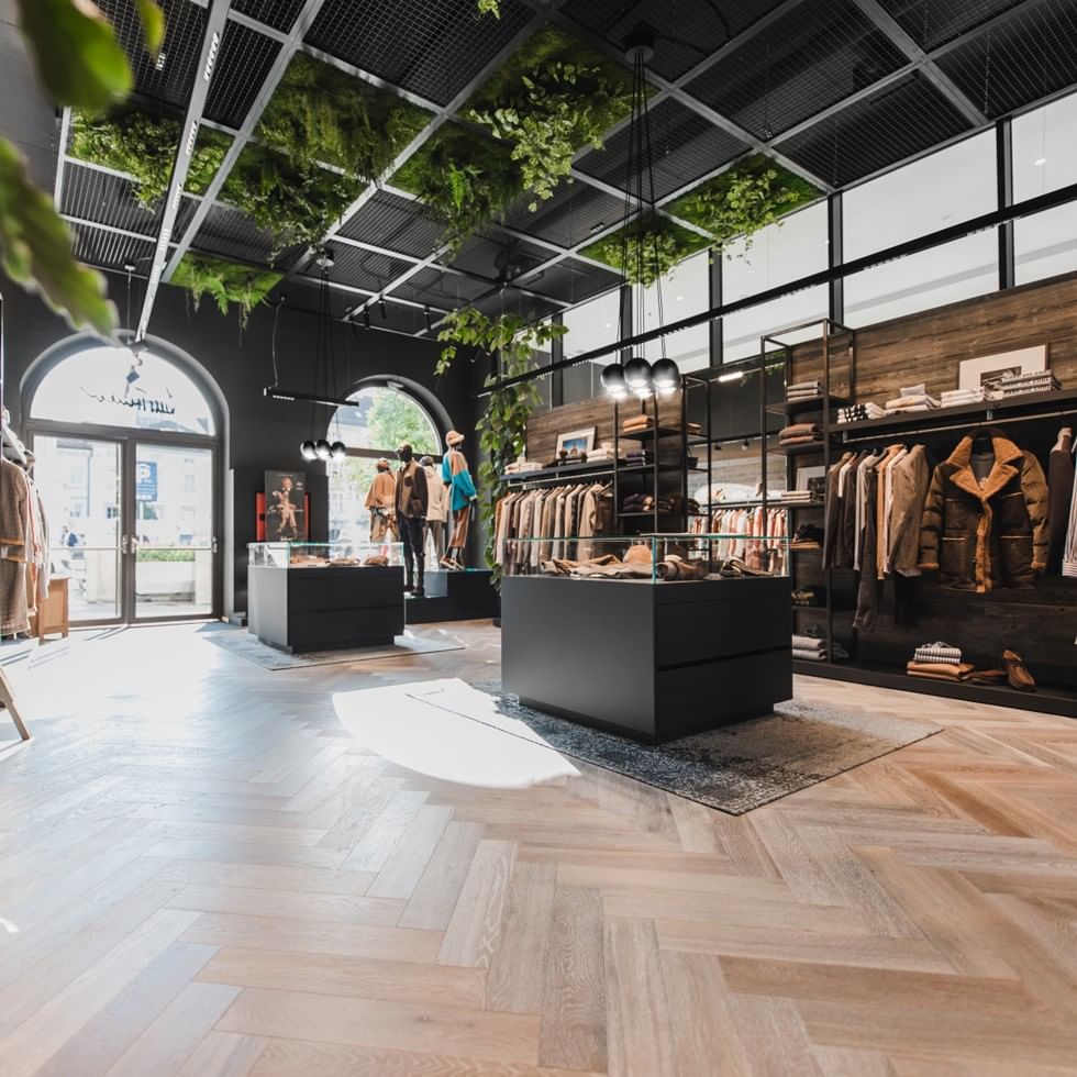 Moderner Boutique-Shop mit hängenden Pflanzen, Kleidung und Schuhen für The Luis Trenker Edit