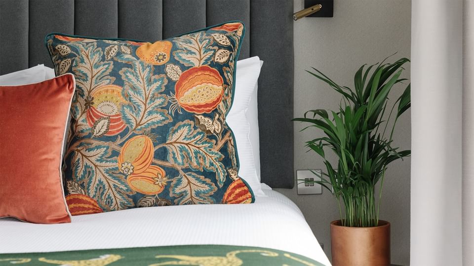 A fresh plant pot by a bed in Cabin Room at The Selwyn Richmond