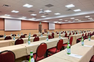Spacious conference room at Hilton Santa Fe Buffalo Thunder with rows of tables and red chairs facing two large screens