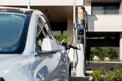 Luxury white electric vehicle charging at the charging station, surrounded by green tropical plants at the Maui Coast Hotel