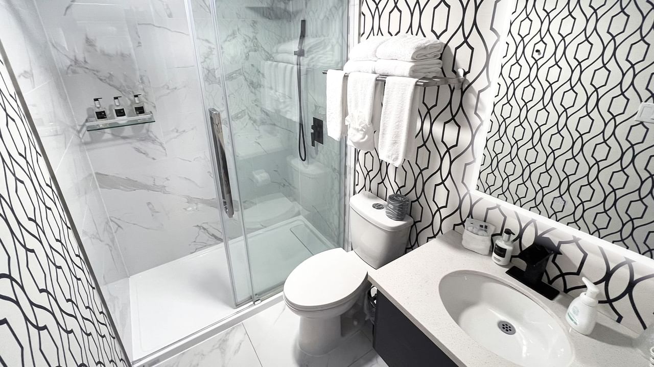 Bathroom with towels, toilet, mirror, shower and sink