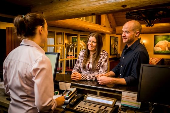 Couple having a friendly conversation with a receptionist at Blackcomb Springs Suites