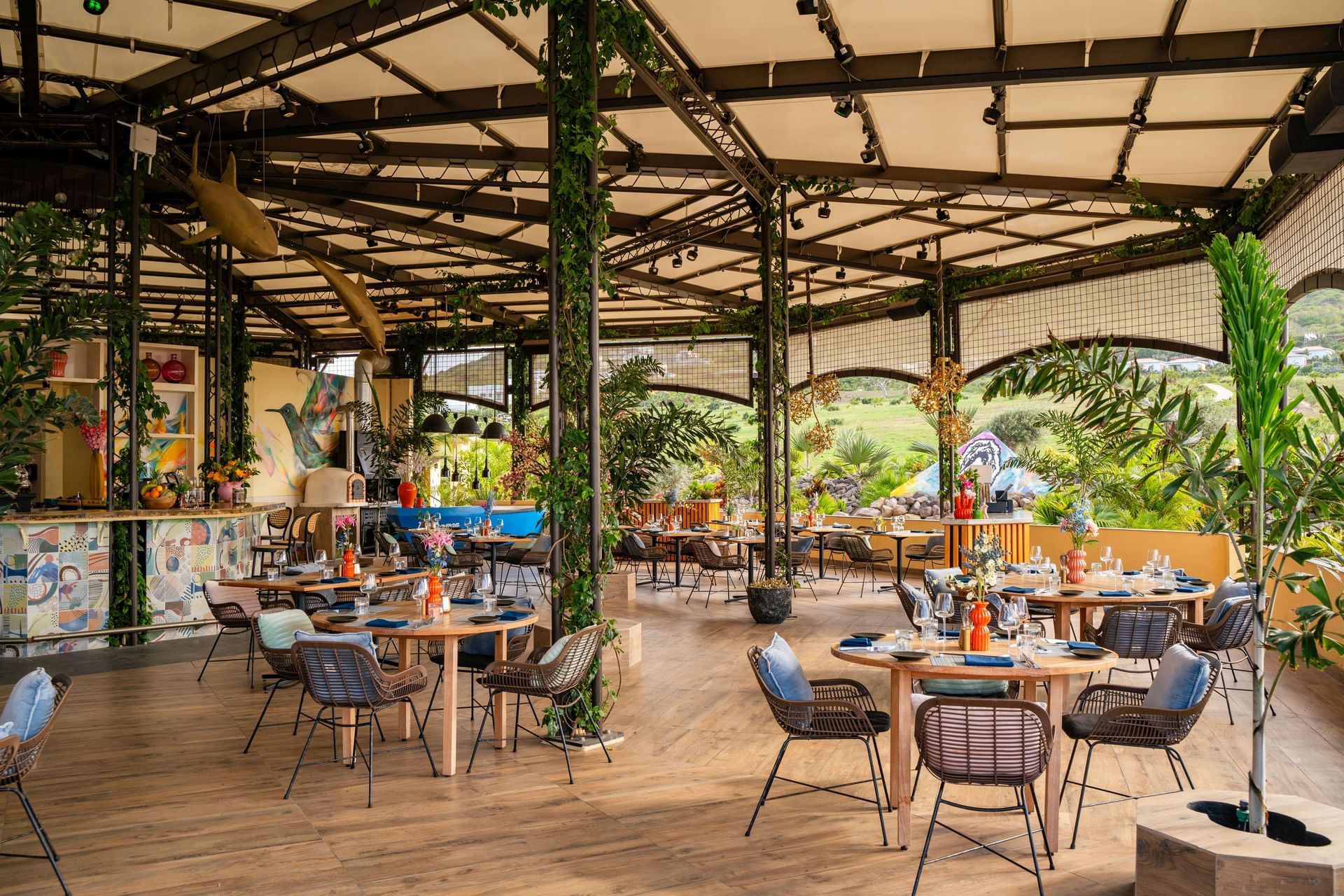 Eetruimte met tafels en gevlochten stoelen, gevuld met kleurrijke decoratie in Bobbie's Beach Club bij Golden Rock Resort