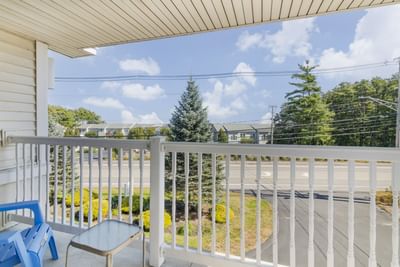 Balcony overlooking tree-lined street under clear sky, with chair and mini table at Ogunquit Hotel and Suites