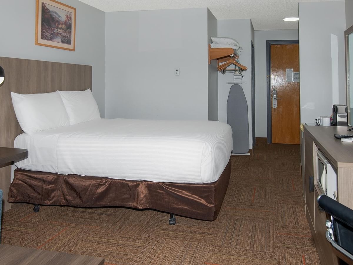 Coast Queen room with white bedding, wood accents, and modern furnishings.