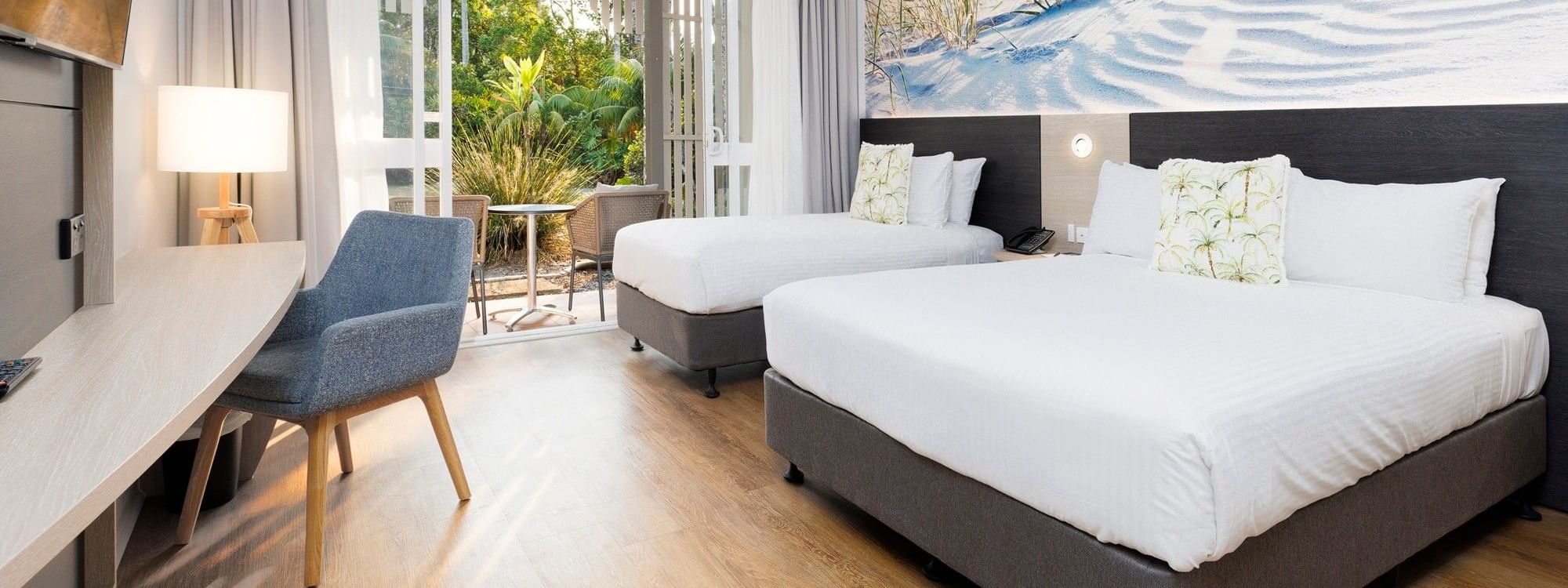 Spacious accessible room with two queen beds, modern furnishings, and balcony access at Novotel Sunshine Coast Twin Waters