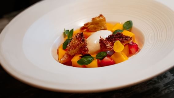 Dessert bowl featuring fresh fruits topped with a scoop of cream served at The Kitchens