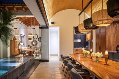 Casa Campanas dining room with a long wooden table and woven pendant lamps by the pool at Singular Signature Residences