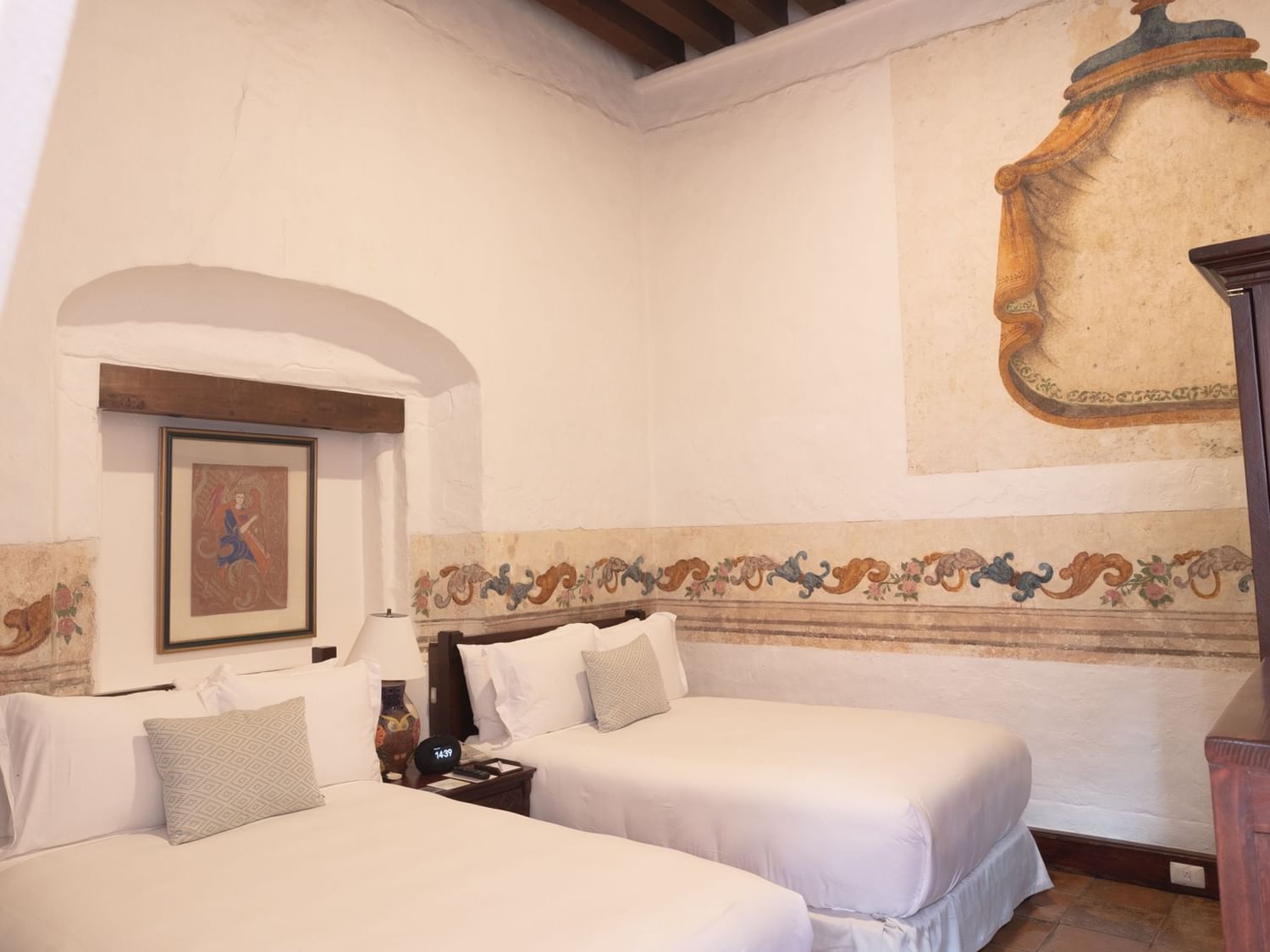 Two double beds in a decorated room with a nightstand and wooden furniture at Quinta Real Oaxaca in Oaxaca de Juarez.