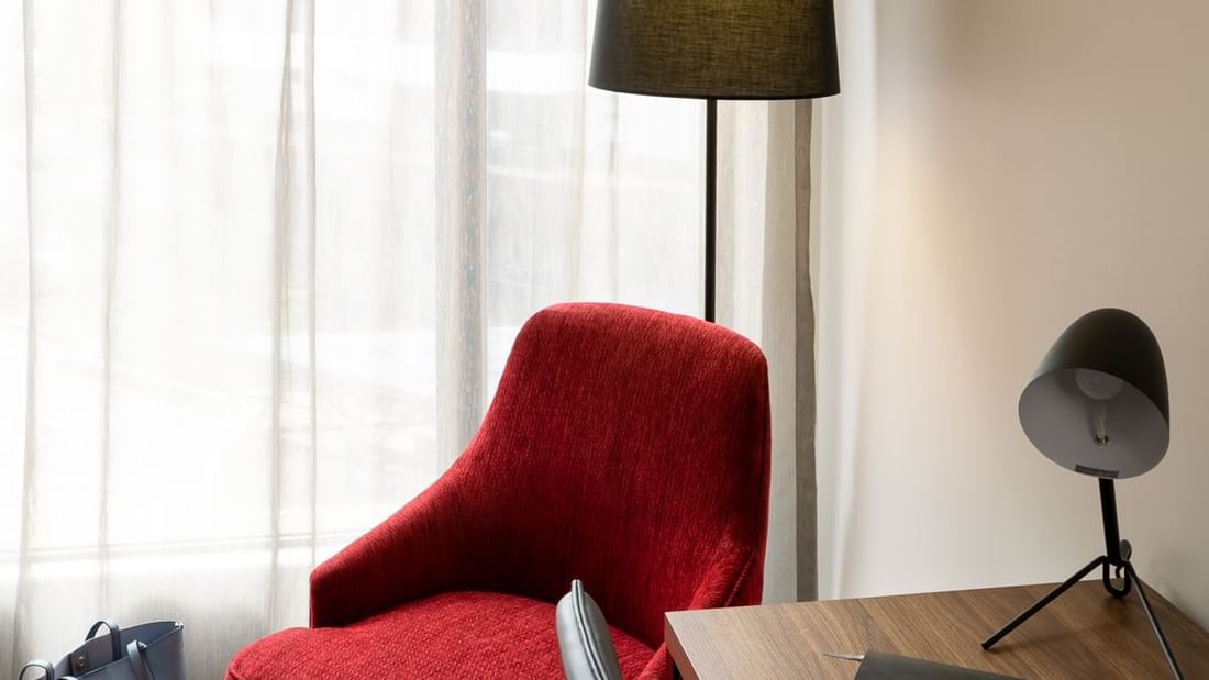 Corner of a Deluxe Room with a red armchair and a wooden desk at Novotel Sydney International Airport