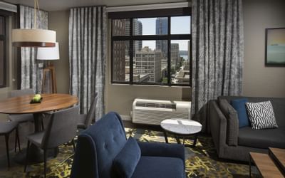 A modern suite at The Paramount Hotel Seattle with a living area, a dining table and city views