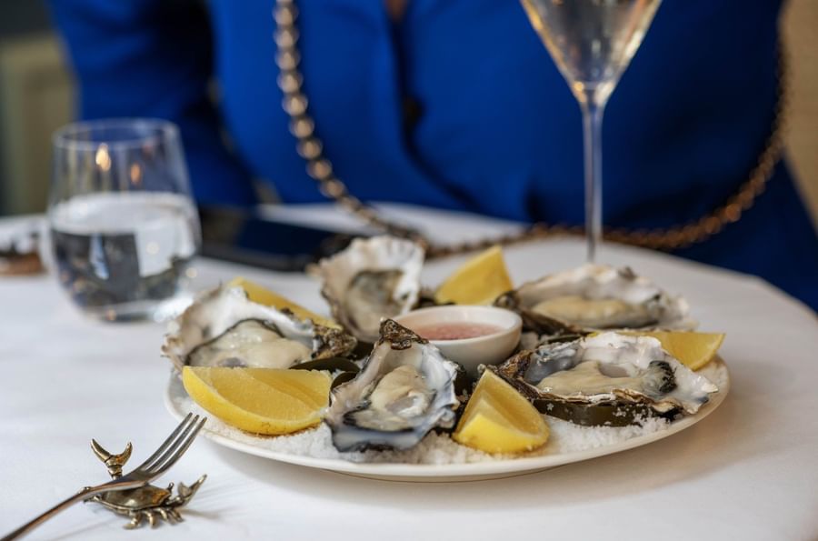 Fresh oysters on a bed of ice with lemon wedges on a plate at The Capital Hotel, Apartments and Townhouse