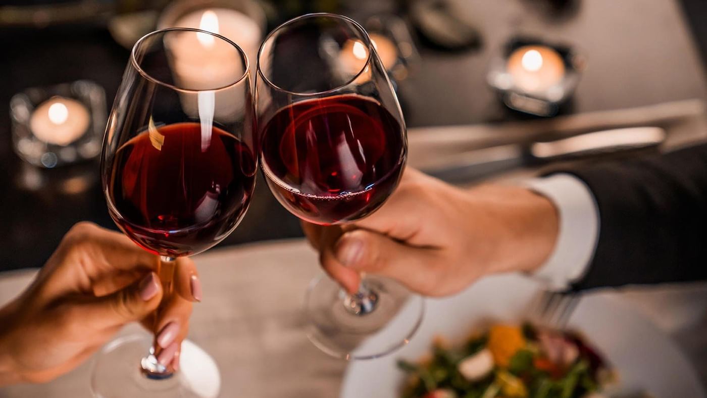 Una pareja brindando con sus copas de vino en FA Hotels & Resorts