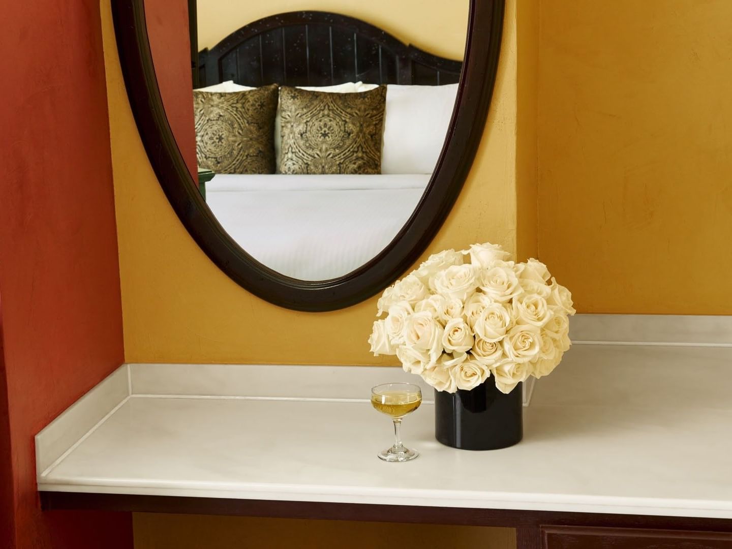 Executive Suite with White roses in a black vase on a marble counter, &  reflected in the oval wall mirror at Petit Ermitage