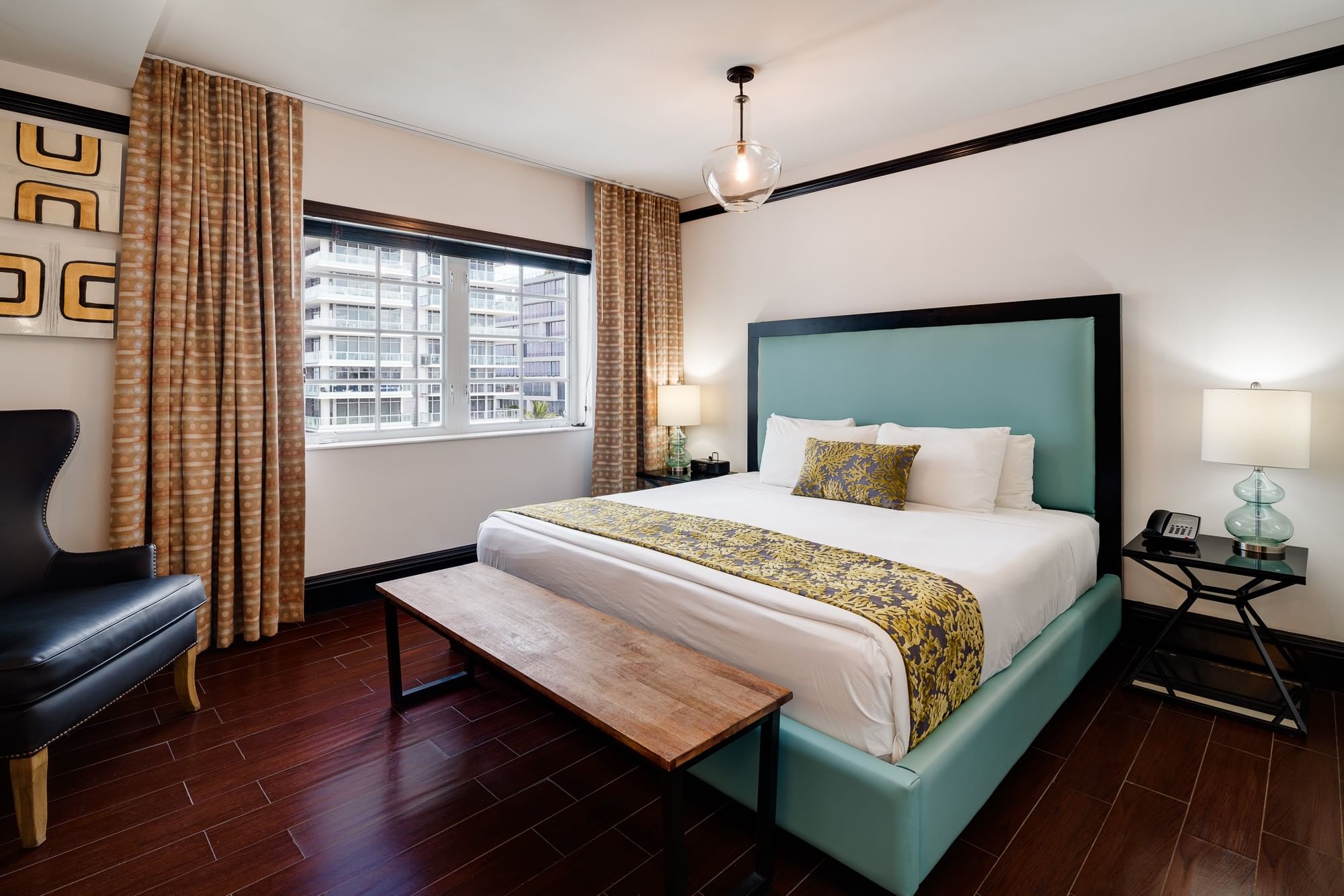 A hotel room with a bed, window, bench, and nightstands.