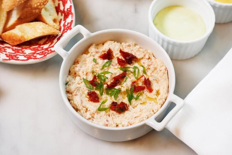 Creamy dip topped with sun-dried tomatoes and green onions, served with toasted bread at family dinner in Park Hyatt Saigon