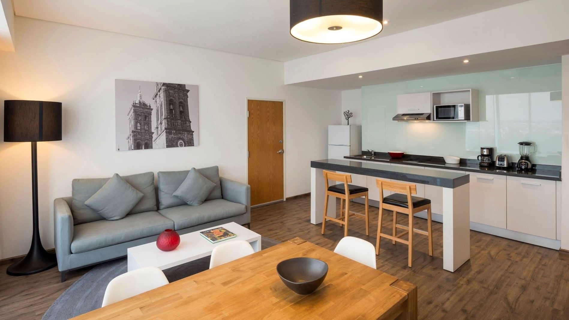 King Suite 2 Rooms with gray couch, coffee table, wooden dining table, and kitchen area at Camino Real Puebla Angelopolis