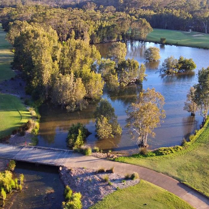 view of golf course and lake with bridge inbetween