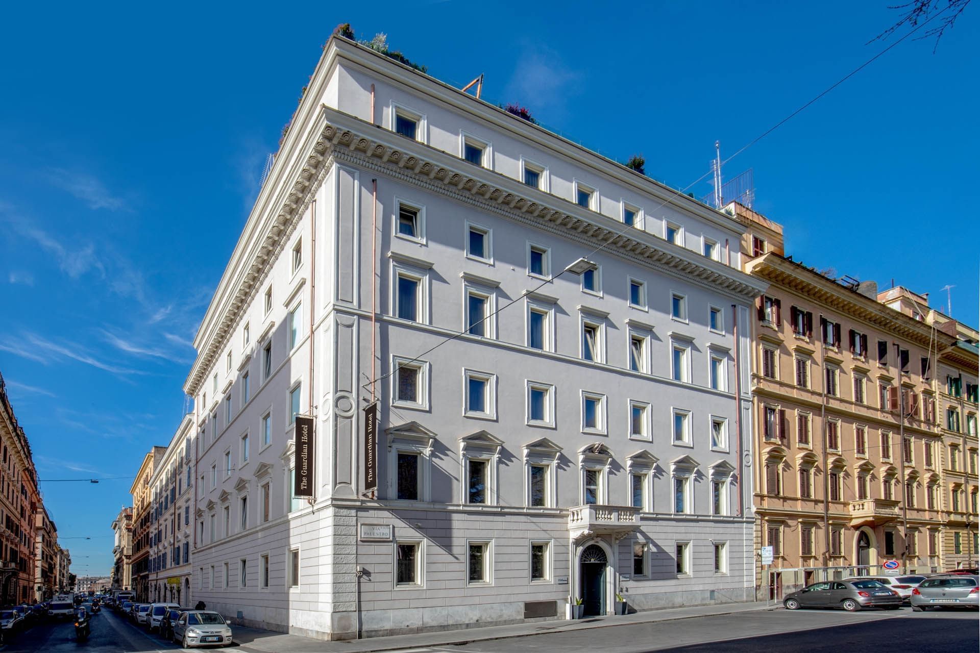 Exterior of The Guardian Hotel with decorative windows, set on a sunny street alongside classic architecture