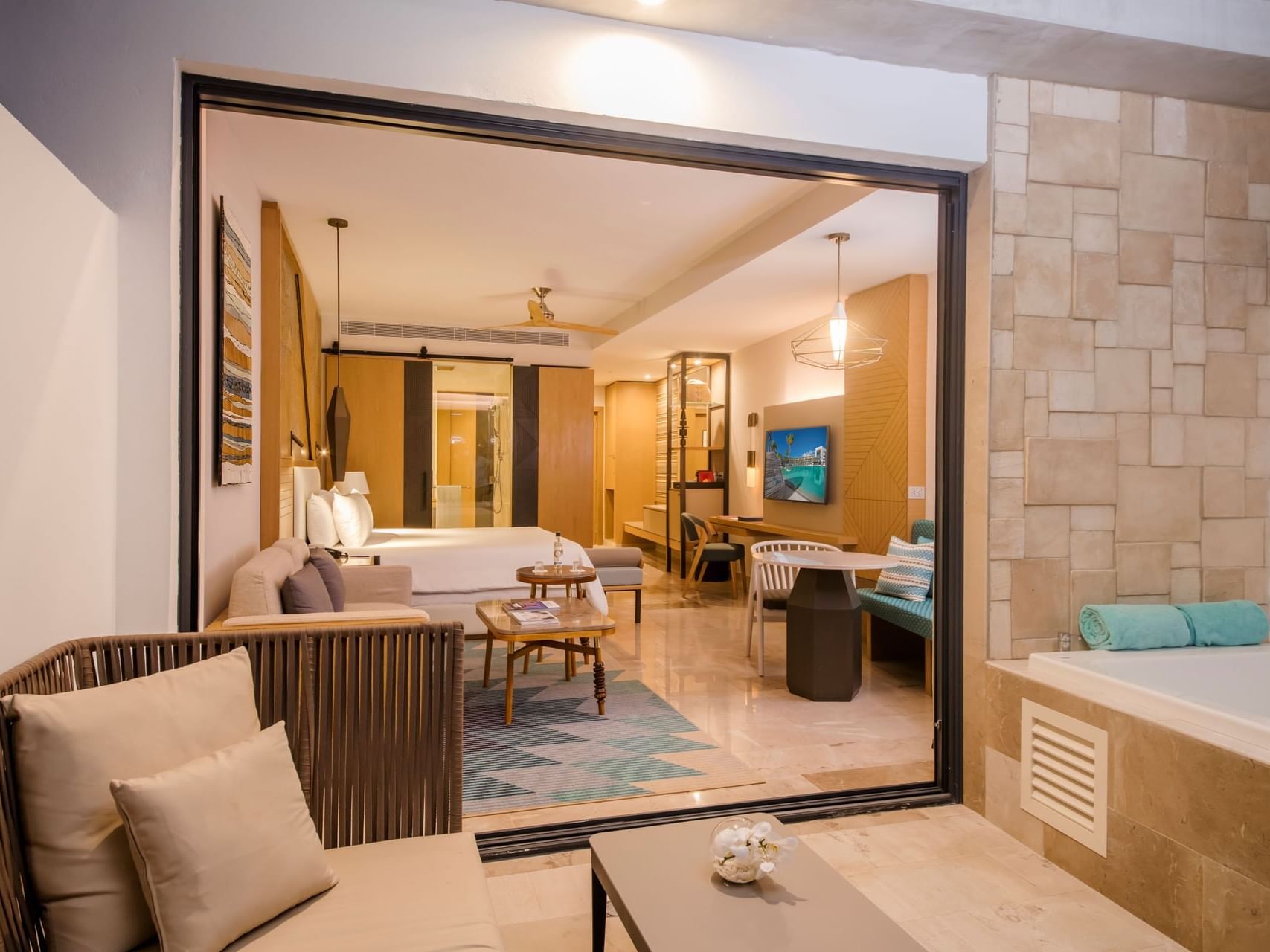 Interior view of Junior Suite with king bed, tv & comfy chairs in at Haven Riviera Cancun