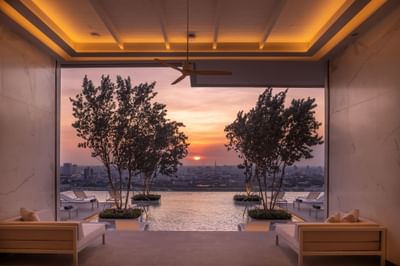 Outdoor swimming pool with sun loungers at Eastin Hotels captured during sunset