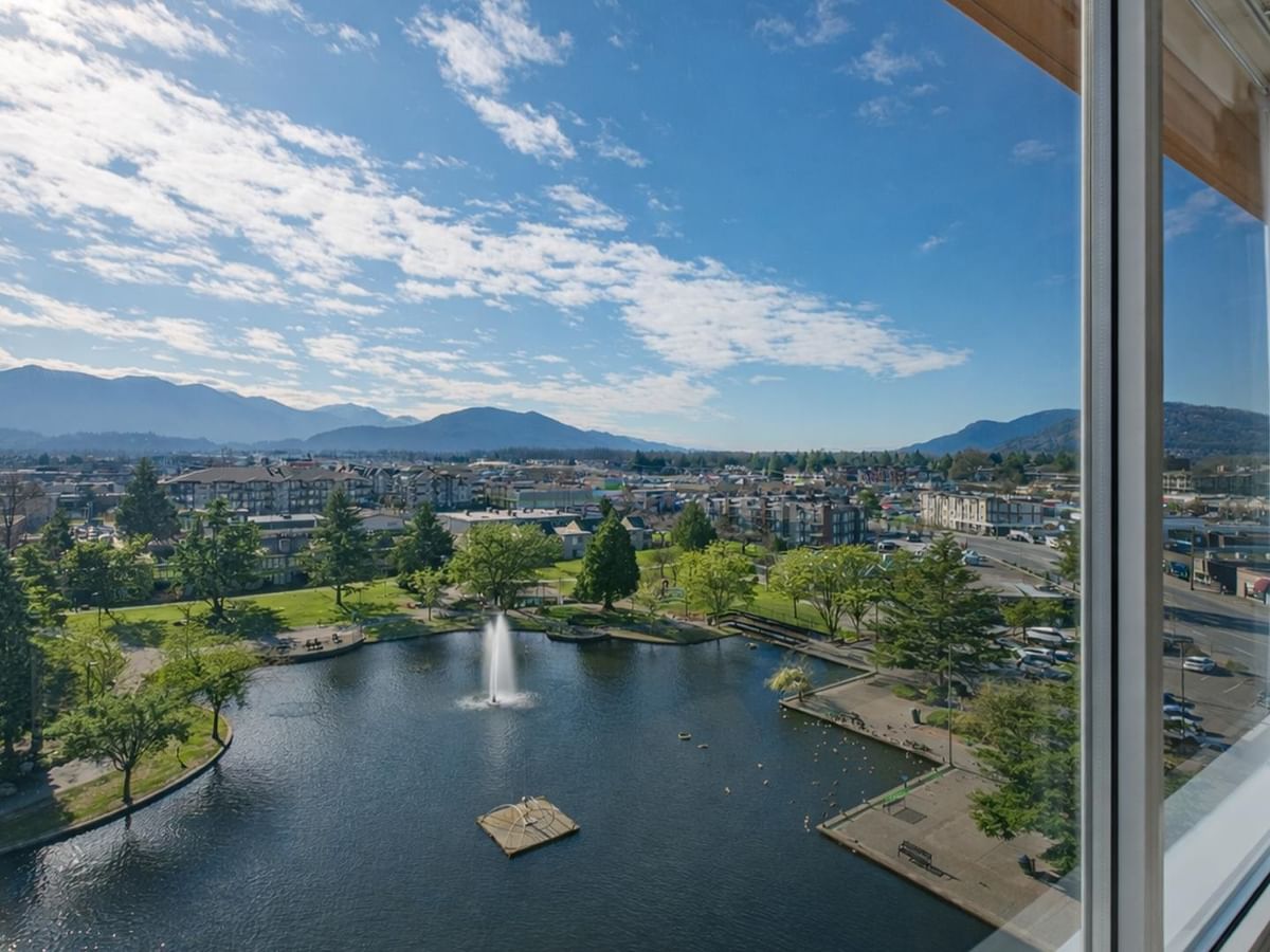 Scenic pond view with fountain and mountains.