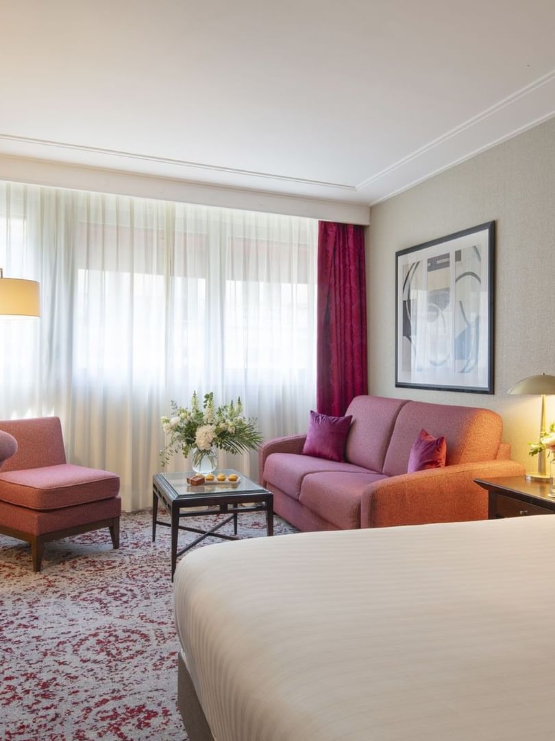 Chambre Executive avec grand lit, coin salon et fenêtre à l'hôtel Warwick Champs-Élysées à Paris.