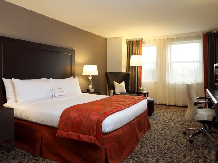 king bed in carpeted hotel room with window
