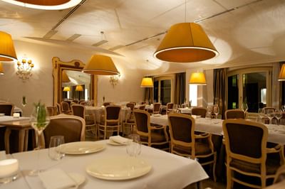 Dining tables set up with glassware, napkins & hanging lamps in a Restaurant at Grand Visconti Palace