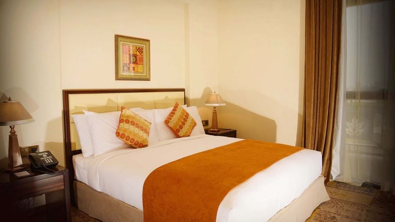 Bedside lamps with wall art in the Business Suite Room at Warwick Al Khobar