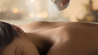 Une personne reçoit un massage avec de l'huile chaude versée d'un récipient.
