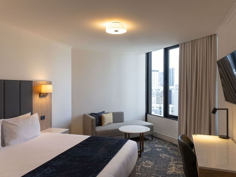 Bed with side lamp and work area in Deluxe King Room at Hotel Grand Chancellor Brisbane