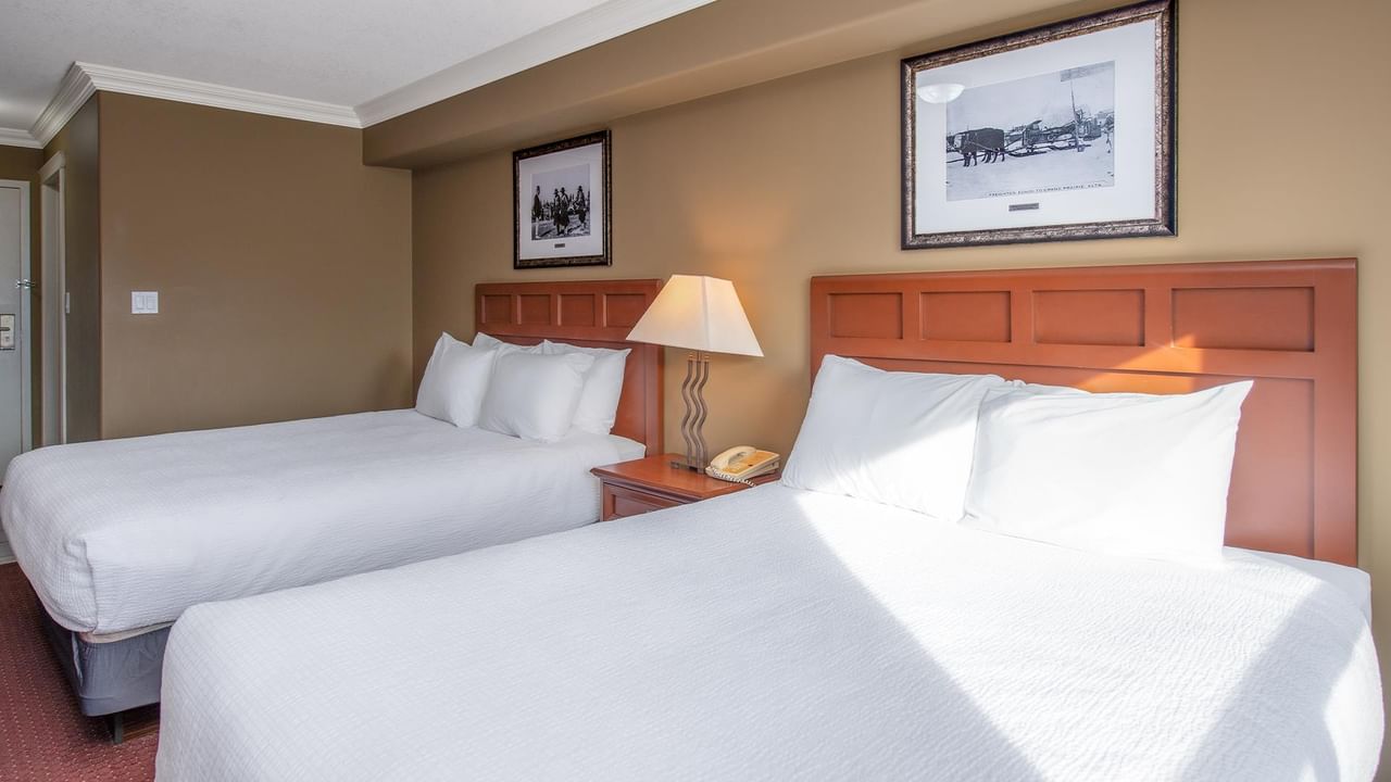 Double room with two beds, wooden headboards, nightstand with lamp, and framed artwork at Coast Edson Hotel.
