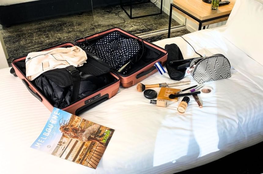 Open luggage with travel essentials on a bed at Brady Hotels Central Melbourne